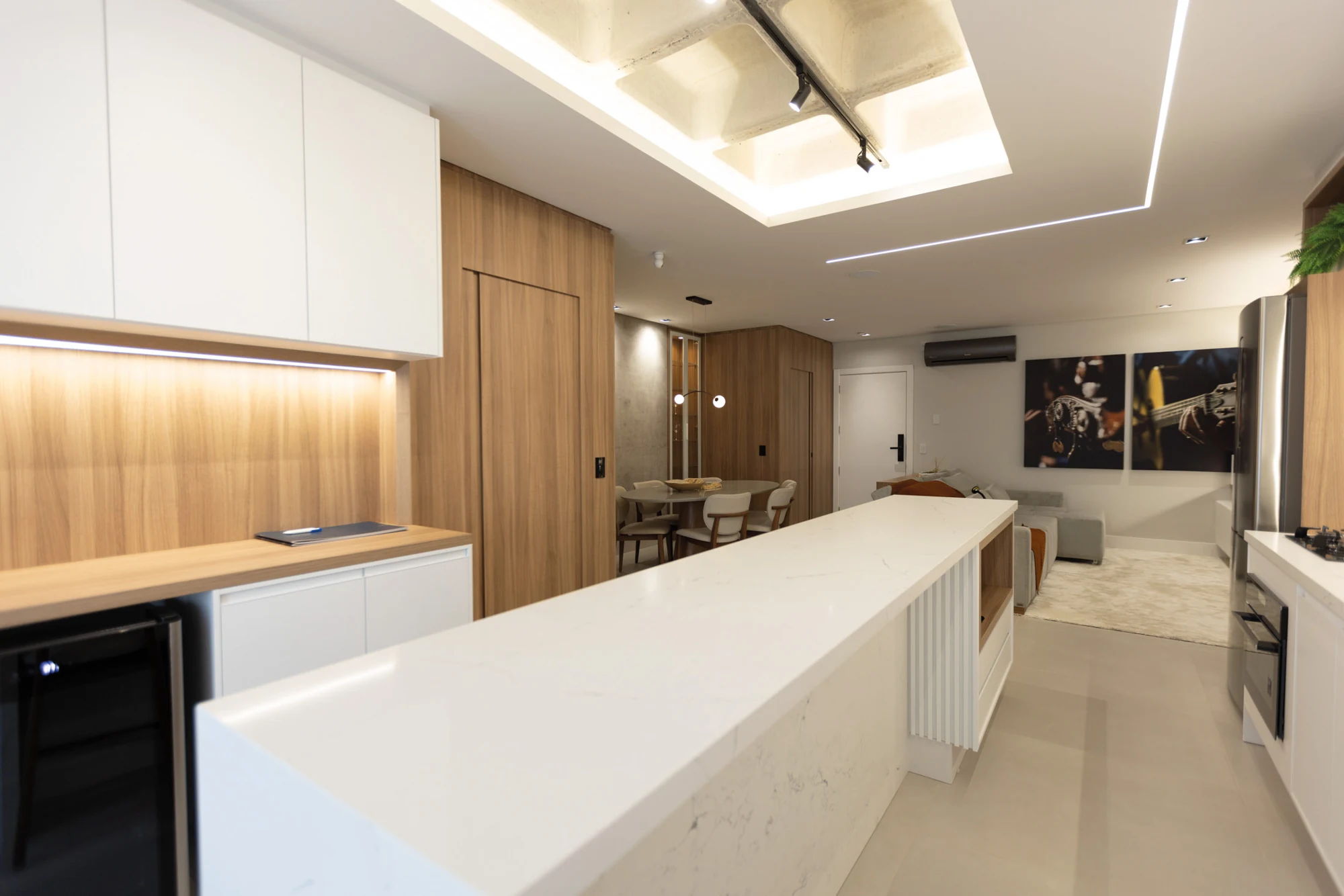 Bancada clara da cozinha do decorado 902, com armários de madeira e vista para o estar