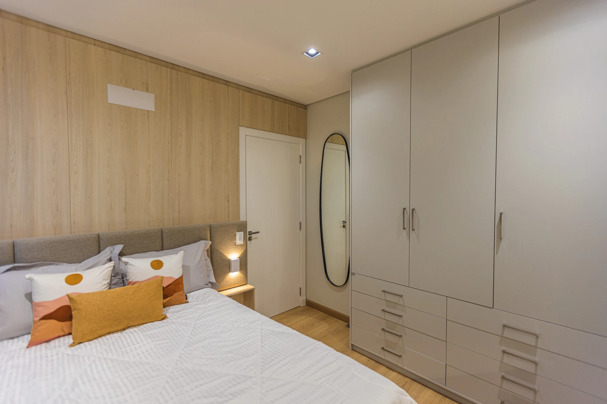 Dormitório com cama de casal, armários claros e detalhes em madeira