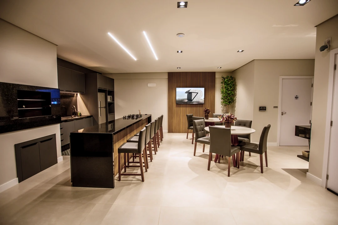 Salão de festas do Cáli Residencial com cozinha integrada, mesa ampla e espaço de estar